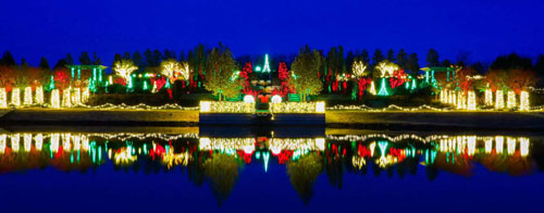 Photo of white, red and green lights decorating the Tandy Floral Terraces garden with reflection on pond taken at dusk