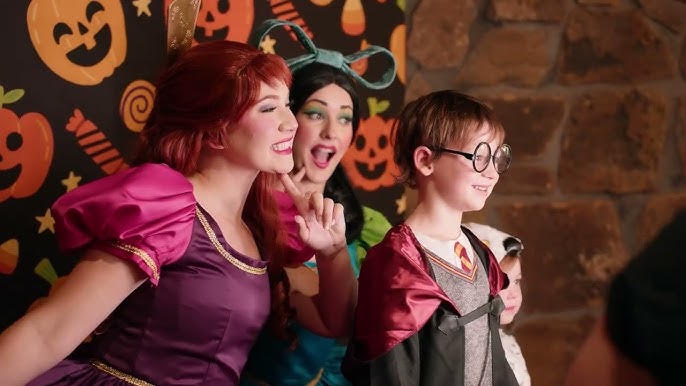 Costumed storybook characters posing for a photo with a young guest at a Halloween backdrop