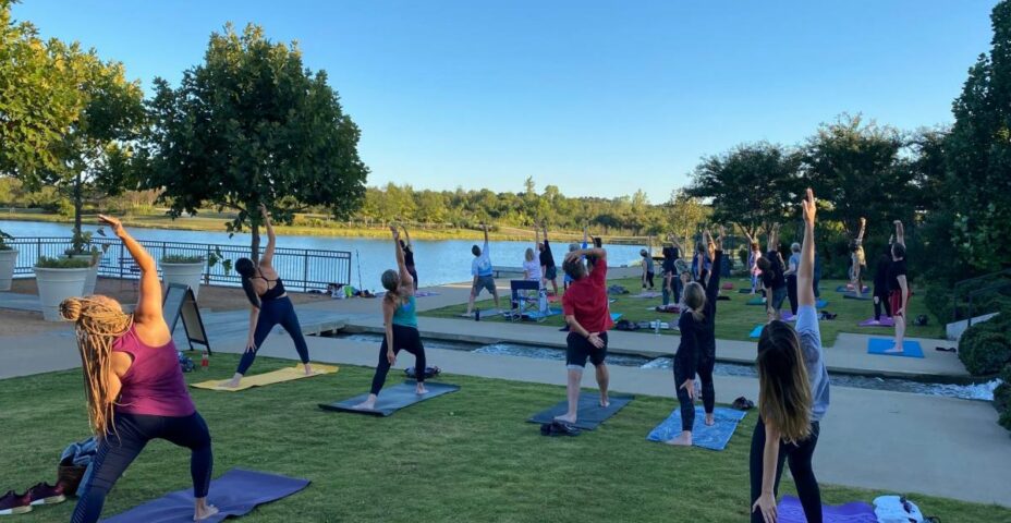 Outdoor yoga class on the lawn beside the lake at Tulsa Botanic Garden